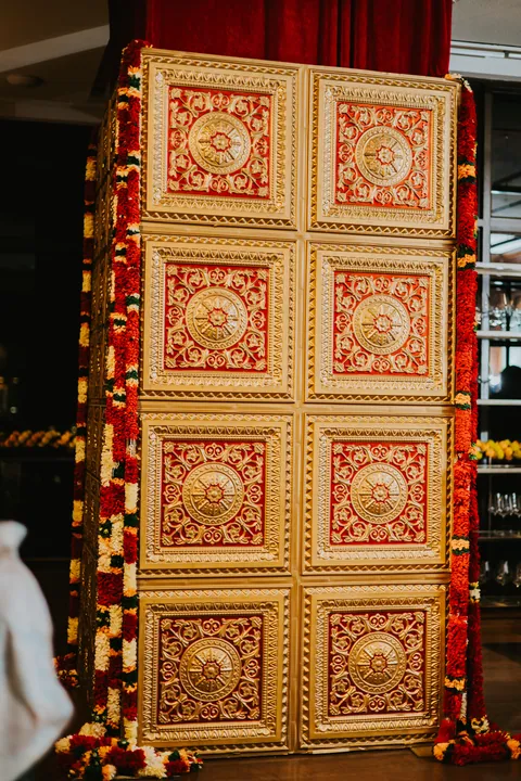 Diwali 2025: Gold carved panel framed in marigold garlands at the entrance