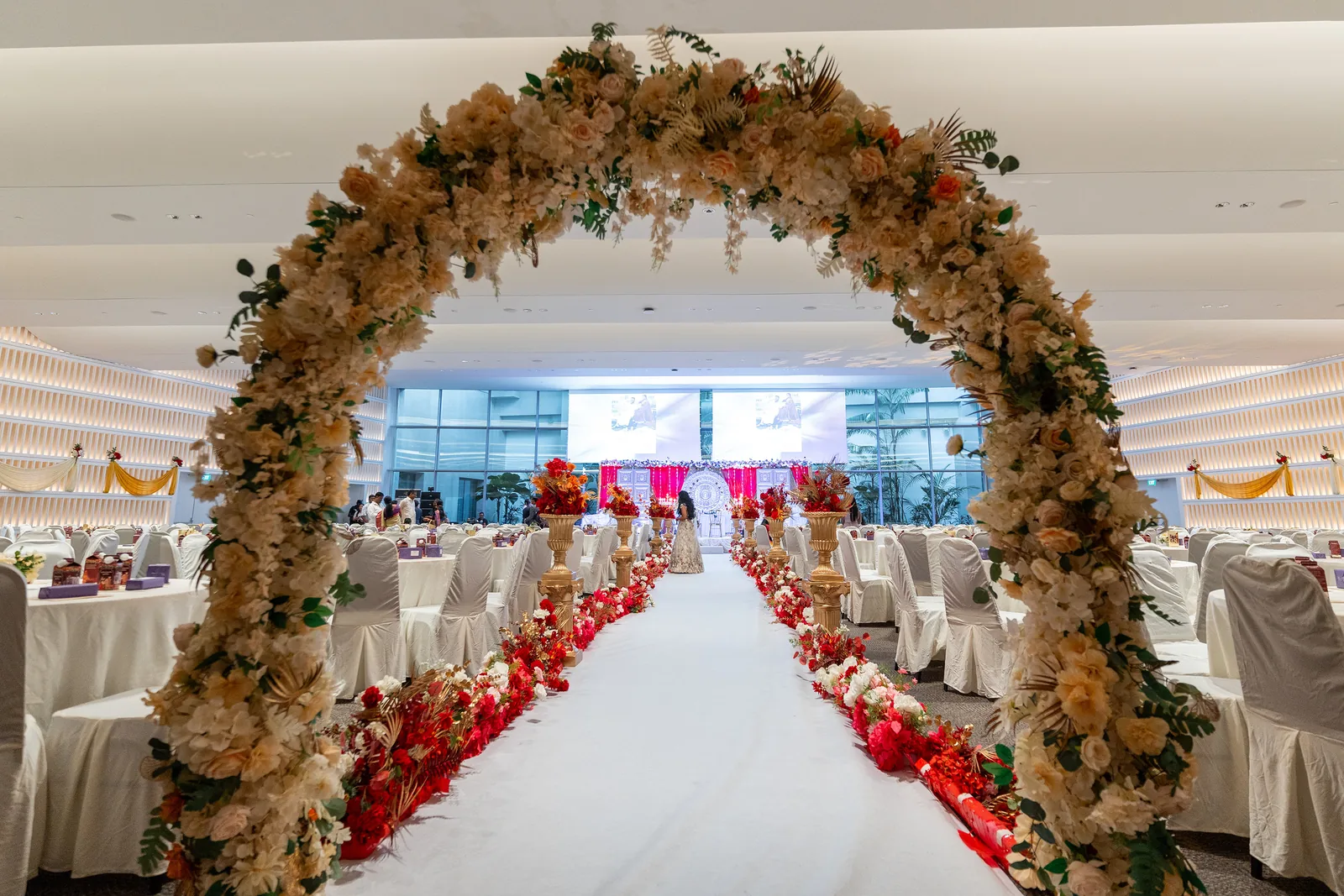 A floral arch and white aisle designed by Alangkaar for a wedding banquet