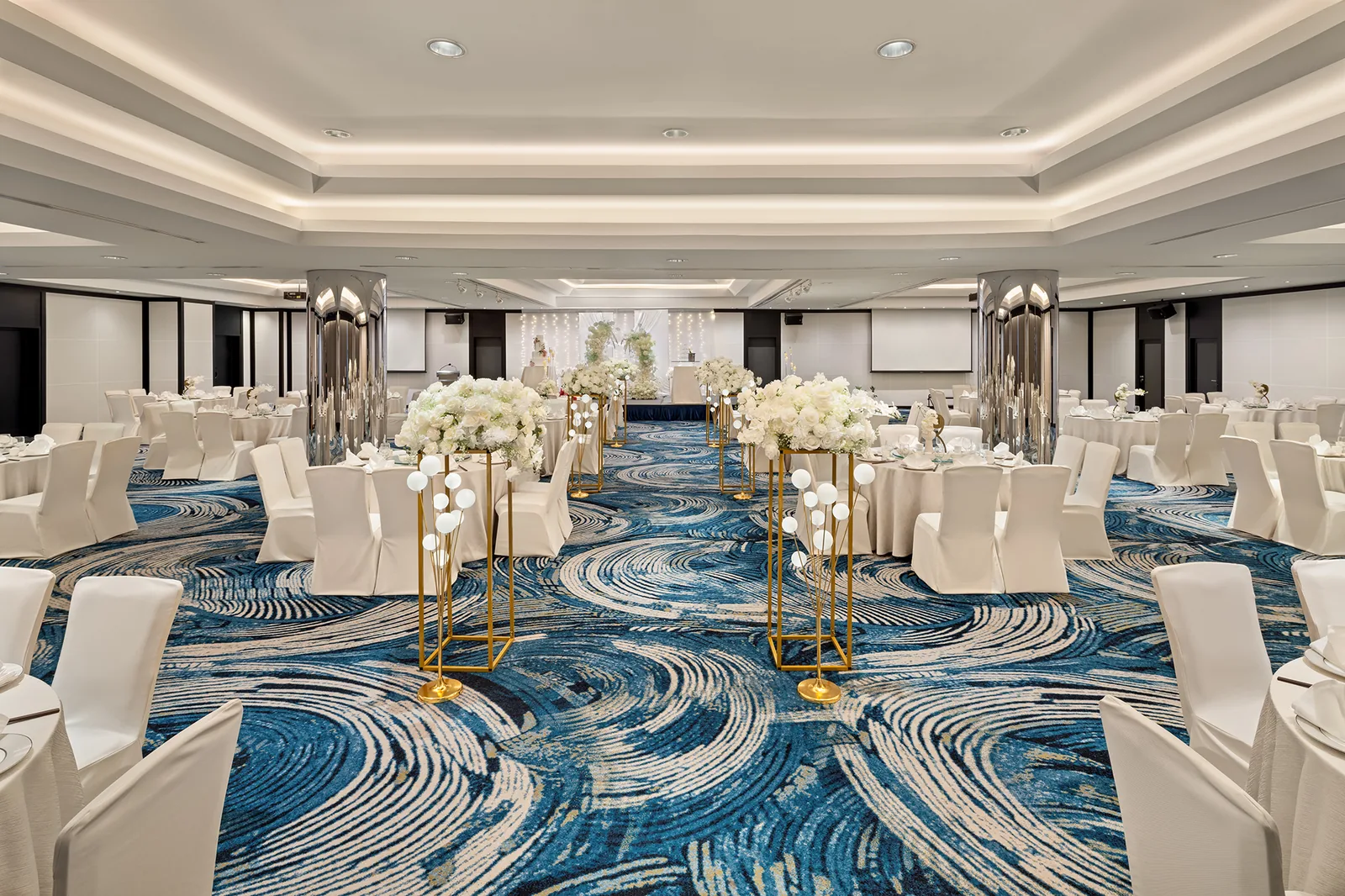 The Atrium Ballroom at Holiday Inn Singapore Atrium, set with round tables and a white-floral aisle to the stage