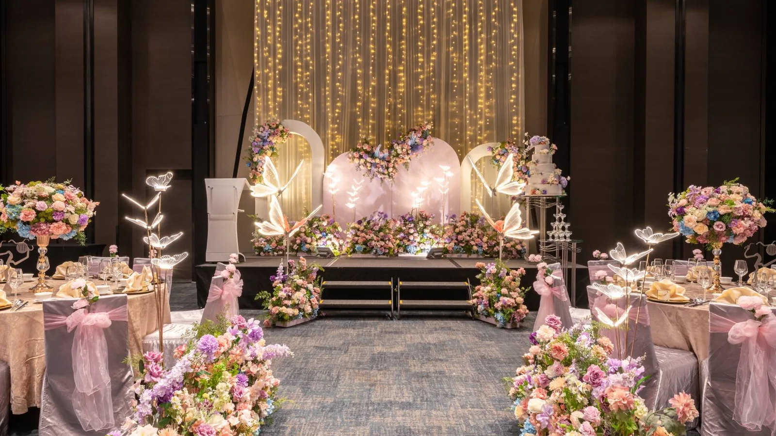 The Polaris Ballroom at Novotel Singapore on Stevens set for a wedding, with a lit stage and a floral aisle