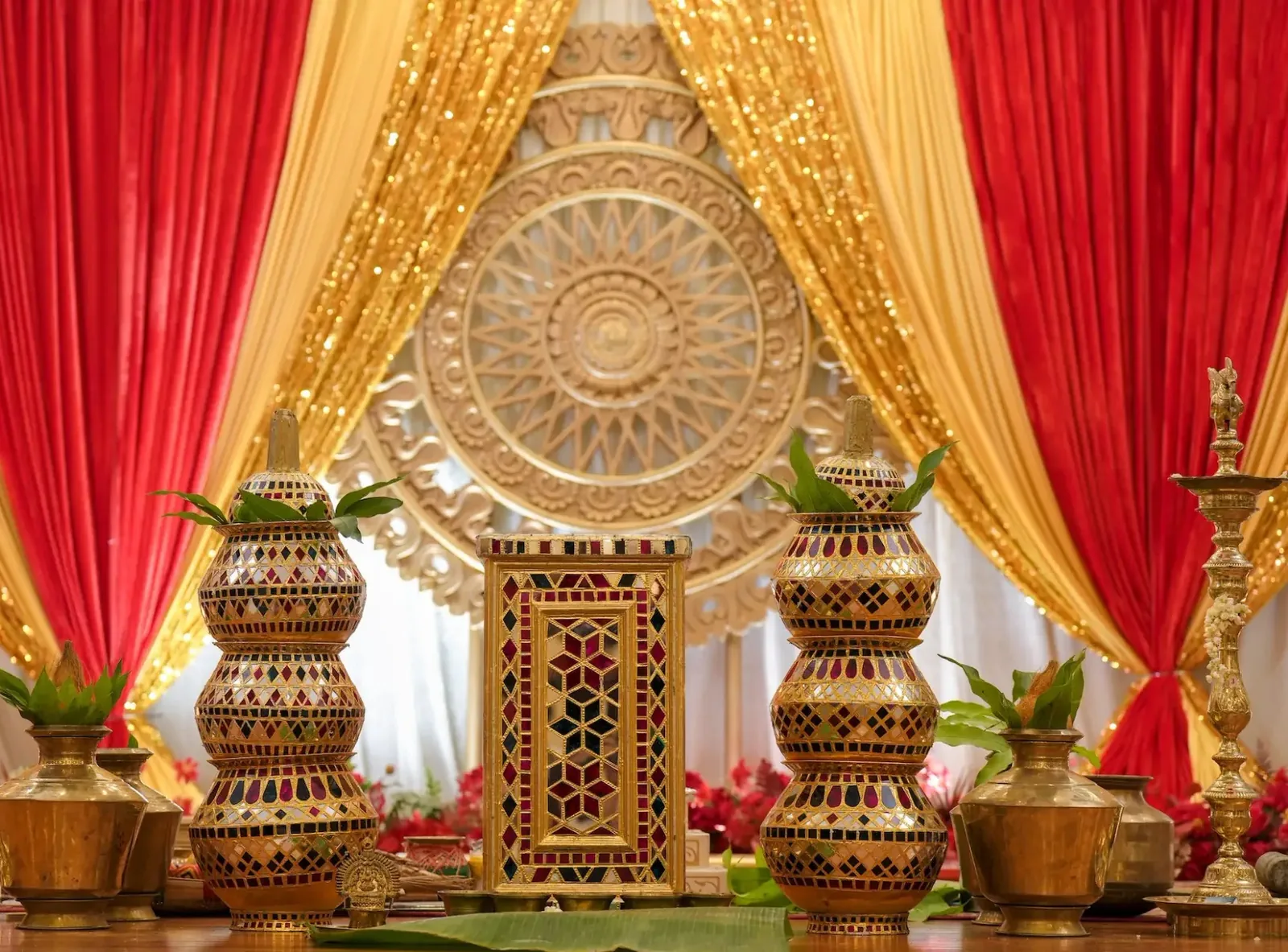 A red and gold wedding stage with kumbam towers and brass lamps, styled by Alangkaar in the wedding hall at Sri Siva Durga Temple