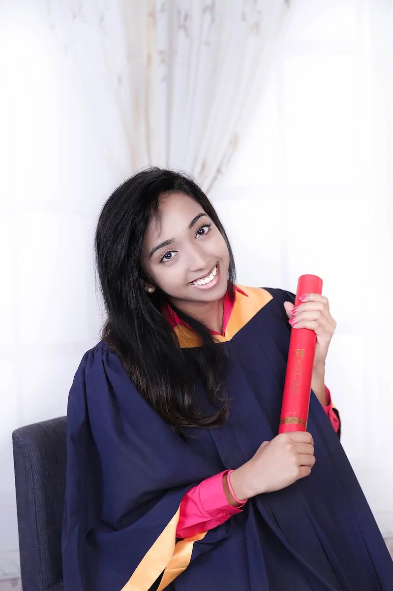 Graduate in gown holding her scroll at an Alangkaar studio graduation photoshoot